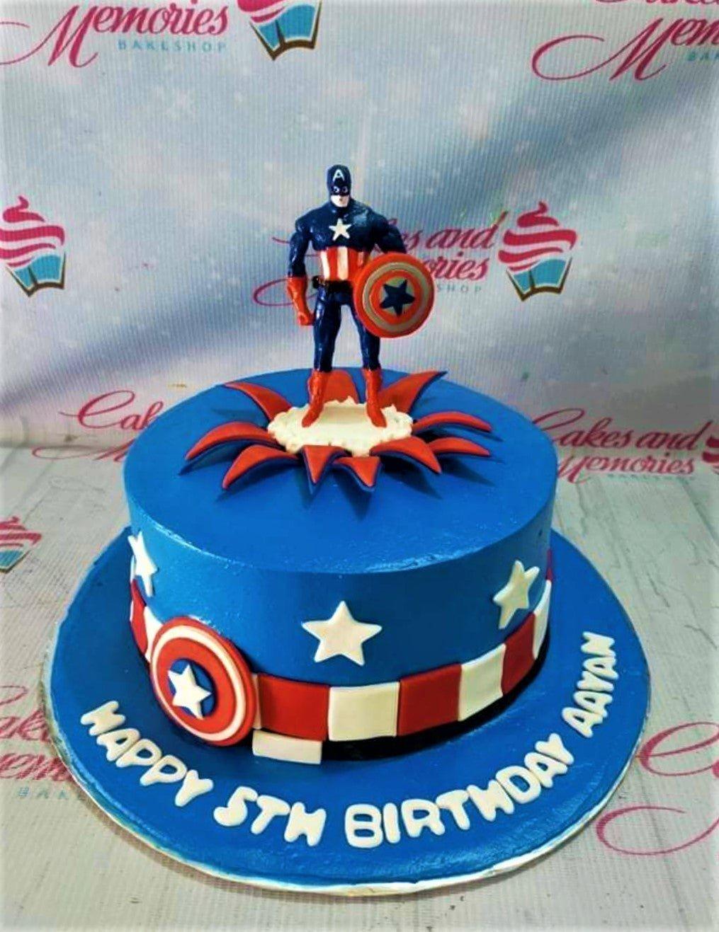 Captain America themed blue birthday cake with a 3D action figure topper and red and white shield patterns.