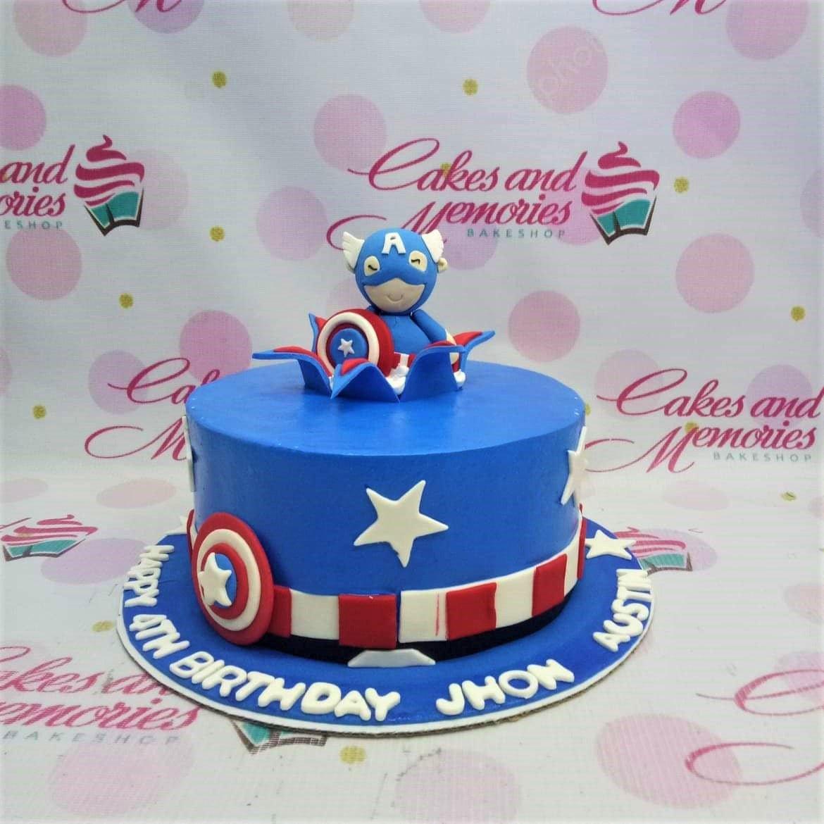 Captain America themed blue fondant cake with a 3D fondant superhero figure, shield, and white stars.