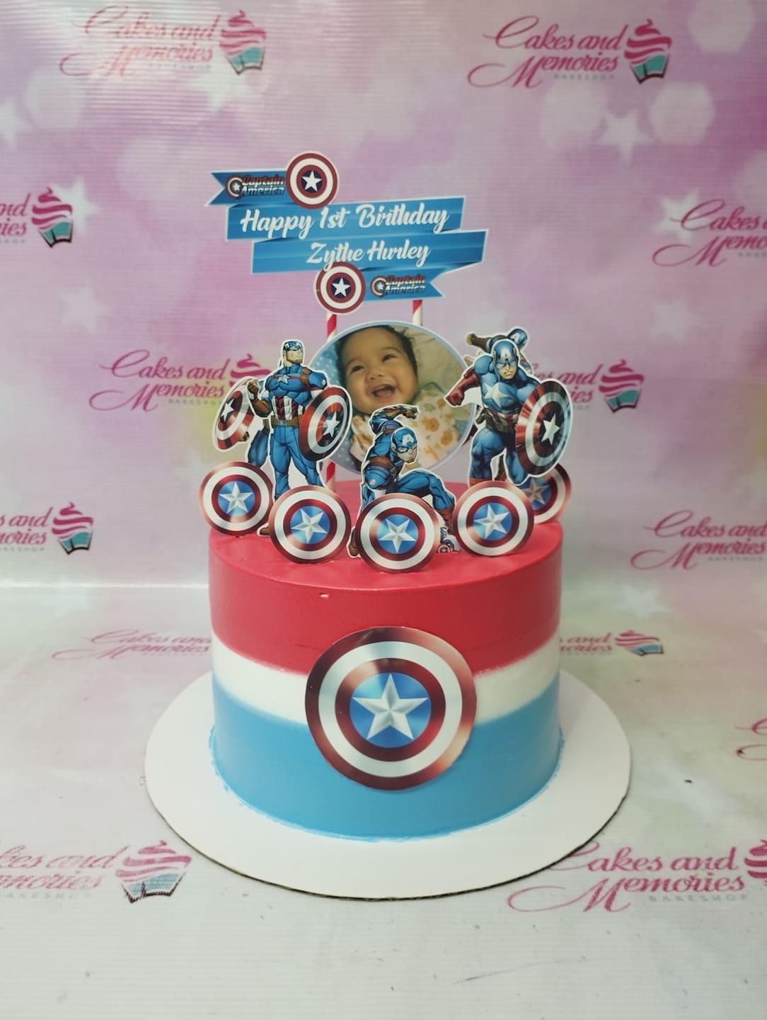 Captain America themed birthday cake with red, white, and blue icing stripes and character printouts.