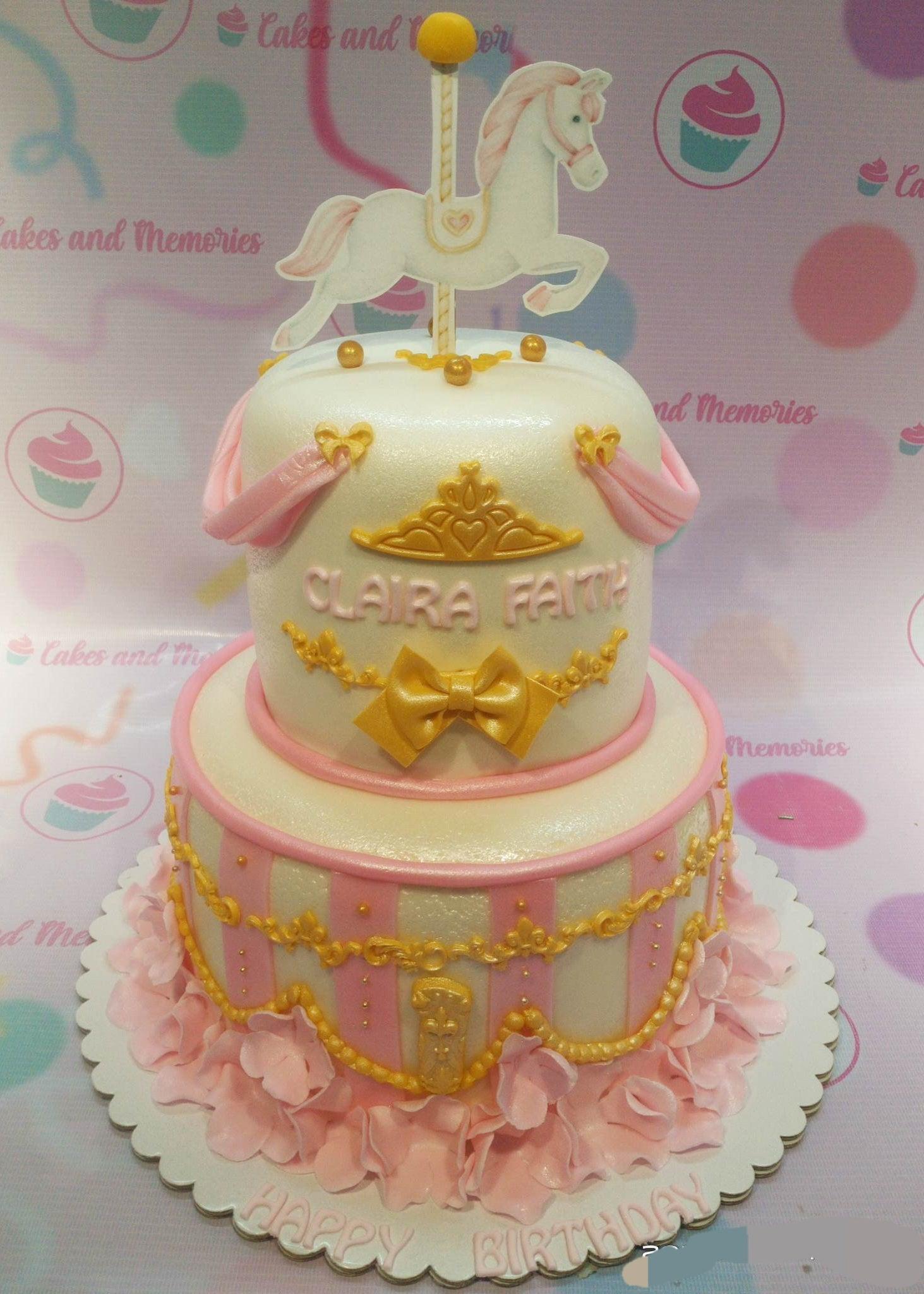 Two-tier carousel themed birthday cake in pink and white with a horse topper, gold crown, and pink ruffles.