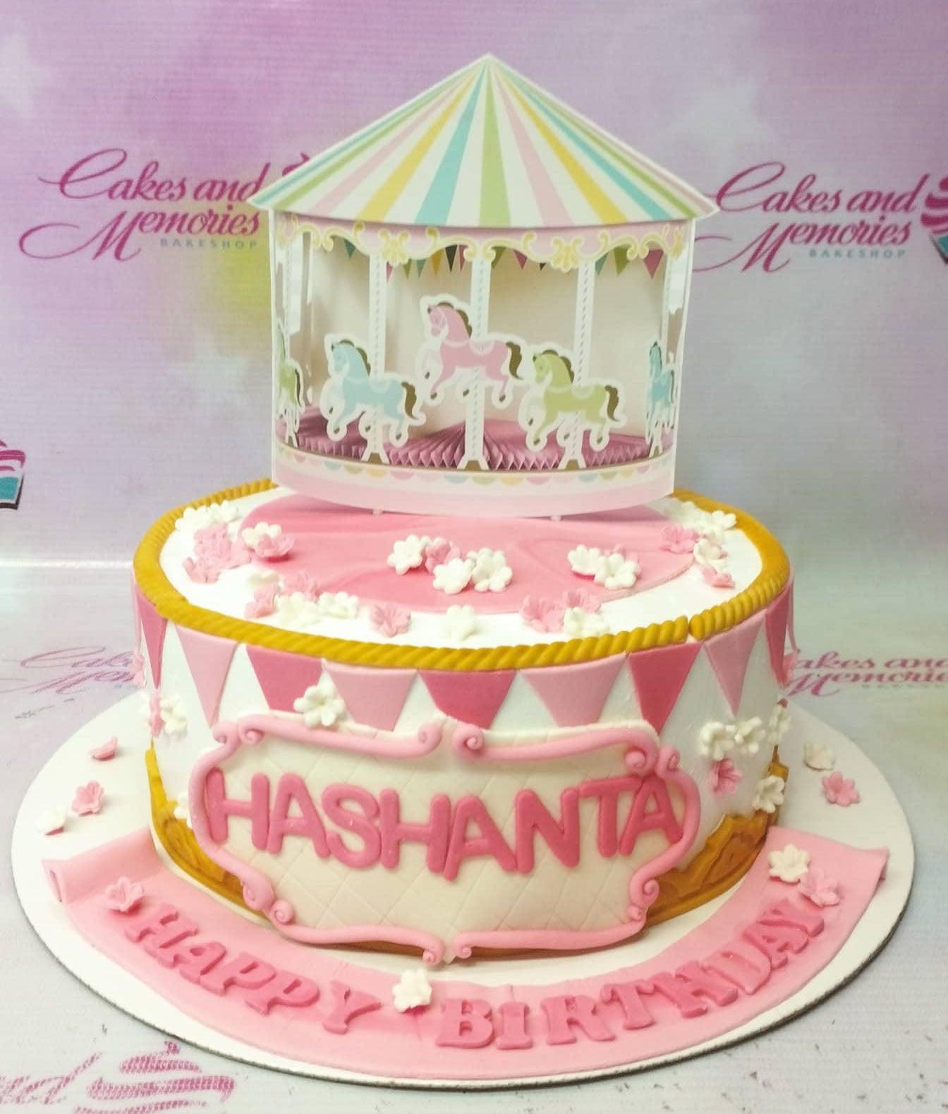 Pink and white carousel themed birthday cake with a large carousel printout topper and pink bunting flags.