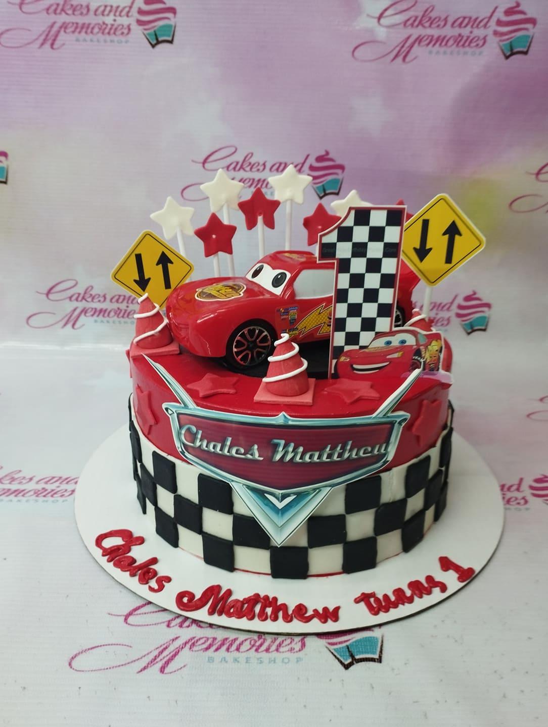 Red Lightning McQueen Cars themed birthday cake with checkered pattern and road sign toppers