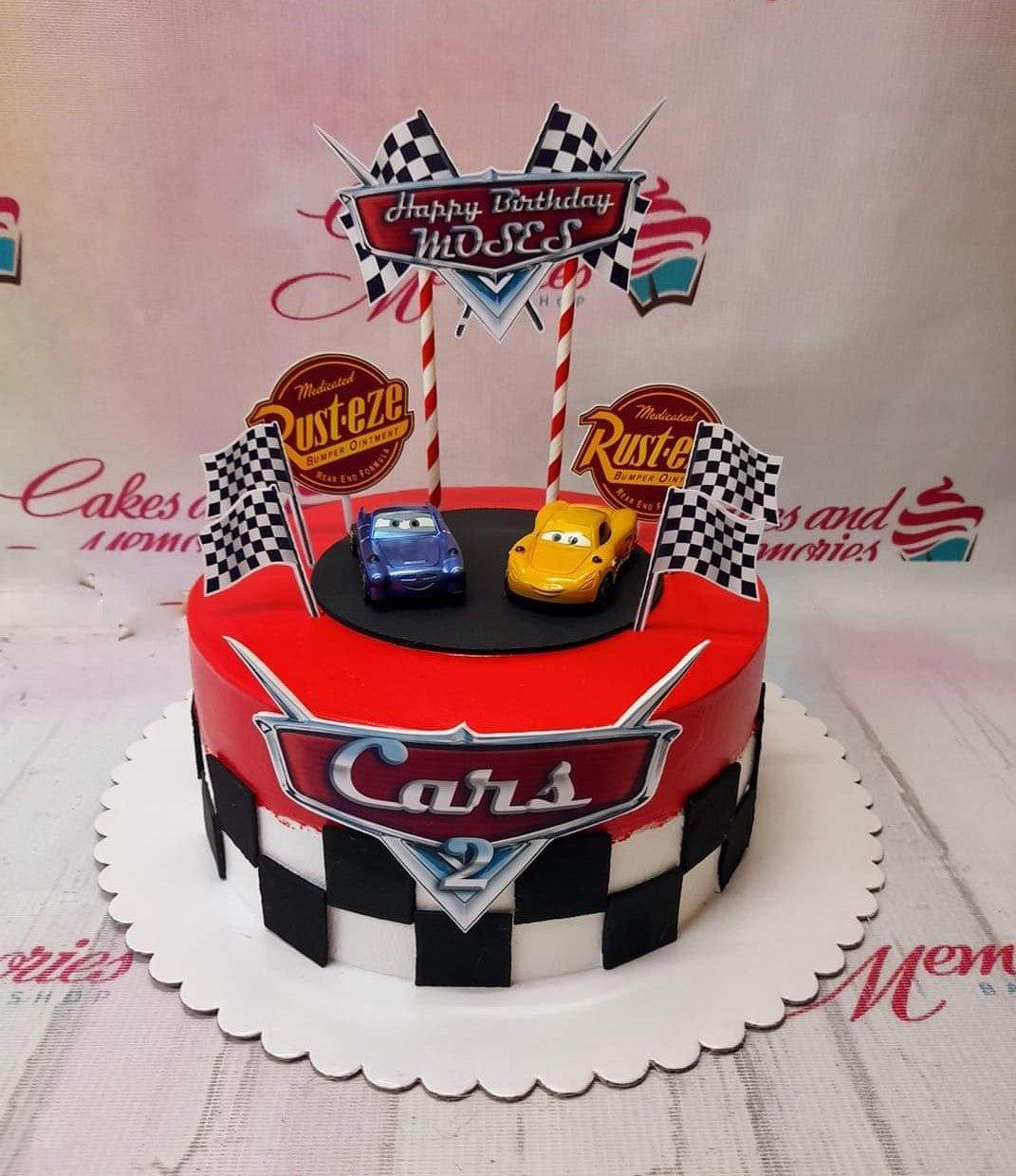 Red Cars movie themed birthday cake with checkered border, toy cars, and racing flag toppers for Moses.