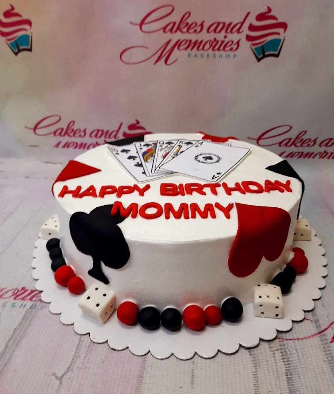 Casino themed birthday cake for Mommy with playing cards, dice, and card suit decorations in red, black, and white.