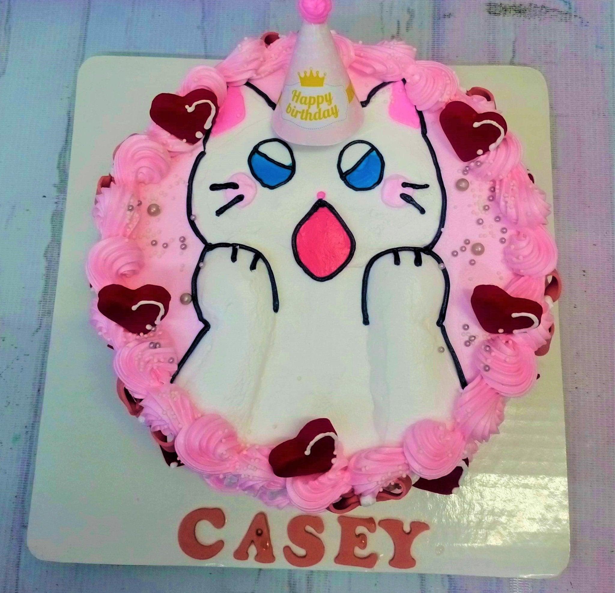 Bento cake featuring a white cat with a pink party hat and red hearts, surrounded by pink icing rosettes and silver pearls.