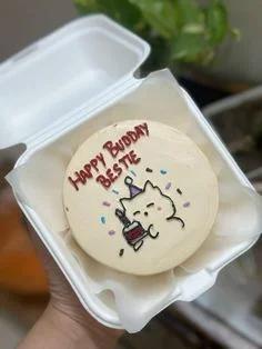 Minimalist bento cake with a hand-drawn white cat holding a small cake and 'Happy Budday Bestie' message in red icing.
