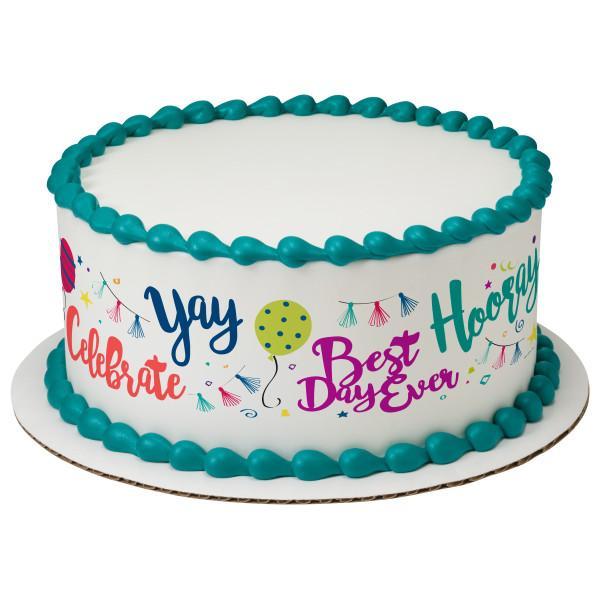 White round cake with teal piped borders and colorful celebratory text and graphics on the side.