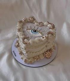 Heart-shaped vintage style cake with ivory icing, piped ruffles, and gold celestial sun and moon decorations featuring a central eye design.