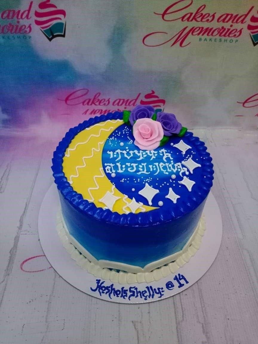 Blue and yellow celestial cake with a crescent moon, stars, and pink and purple roses on top.