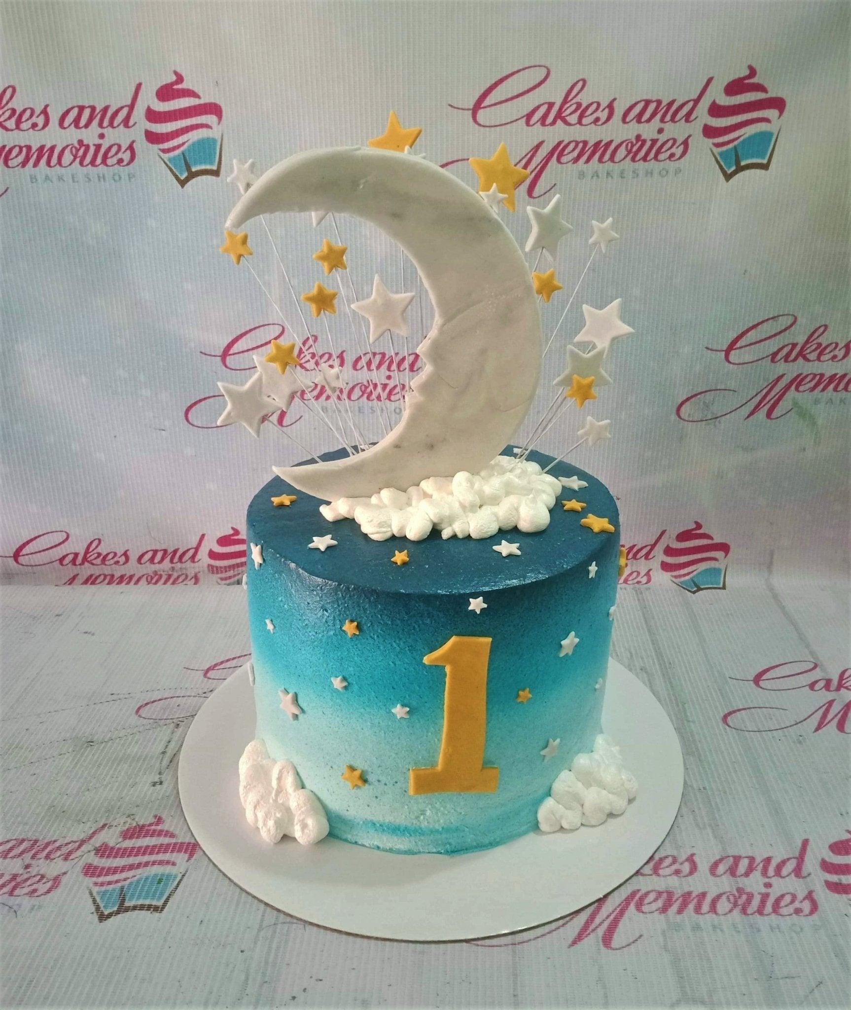 Blue gradient ombre cake with a large white crescent moon, yellow and white stars, and fluffy white icing clouds.