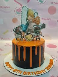 Black cake with orange drip and Chainsaw Man character printouts on top