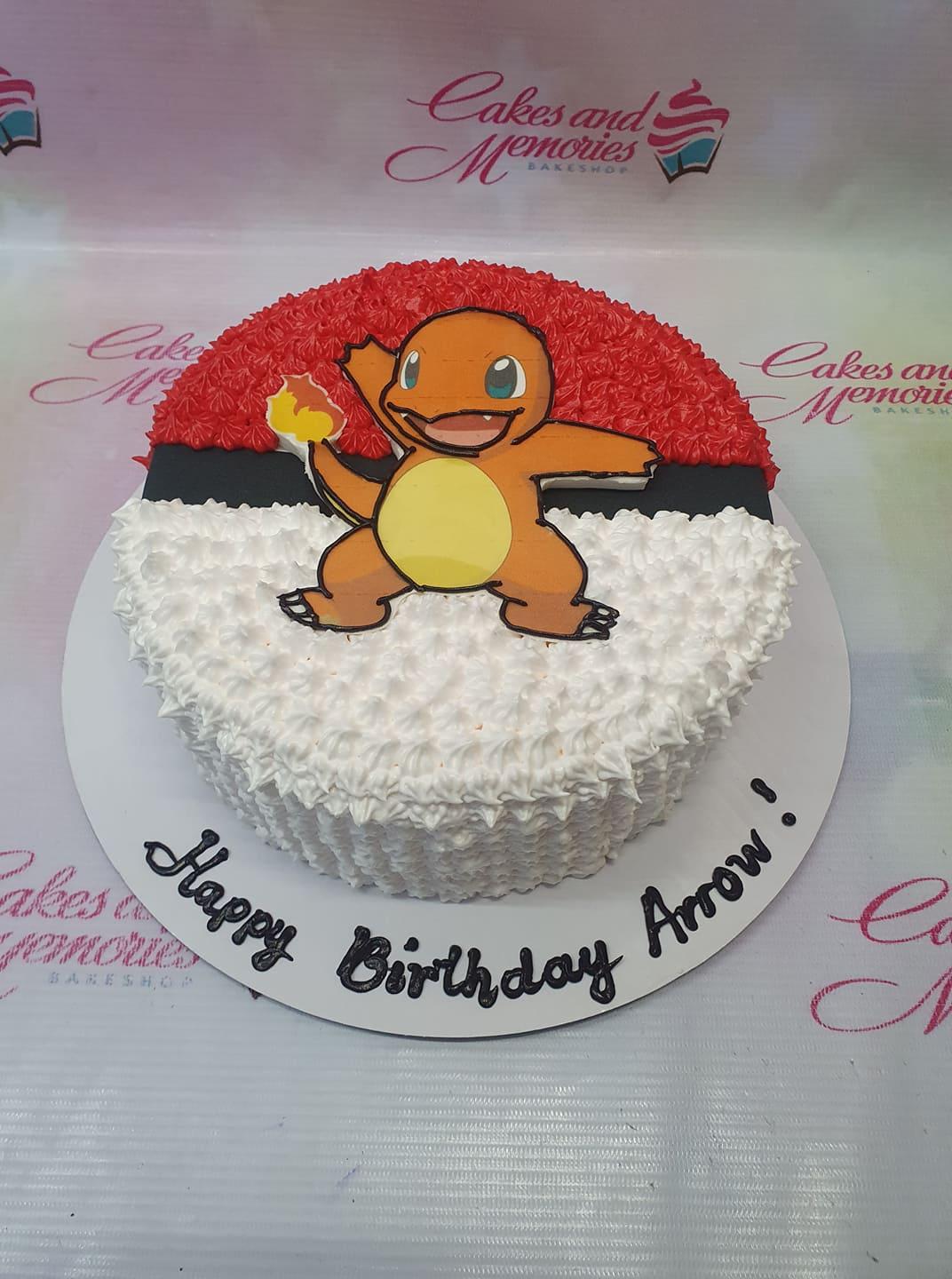 Pokeball themed birthday cake with a Charmander character printout and red and white icing rosettes.