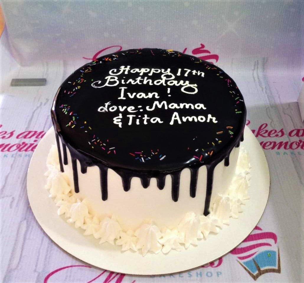 White 1-tier birthday cake with dark chocolate drip, colorful sprinkles, and white icing rosettes at the base.