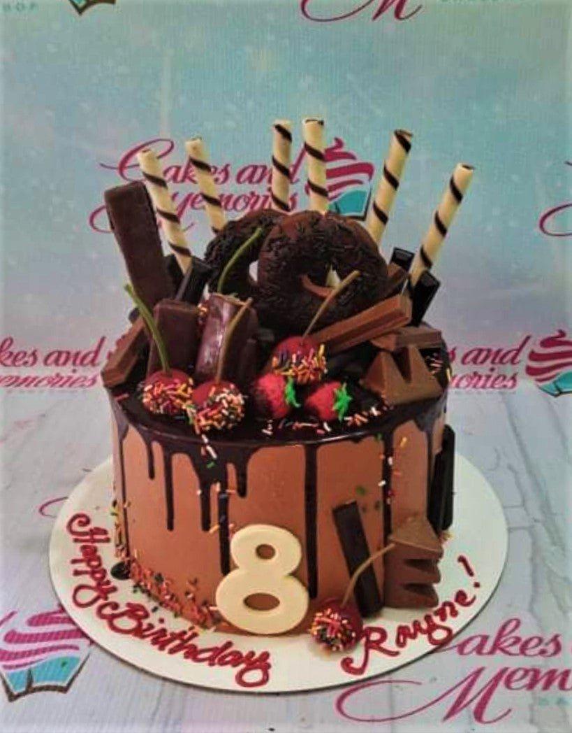 Chocolate drip cake with chocolate donuts, strawberries, and wafer sticks for an 8th birthday celebration.
