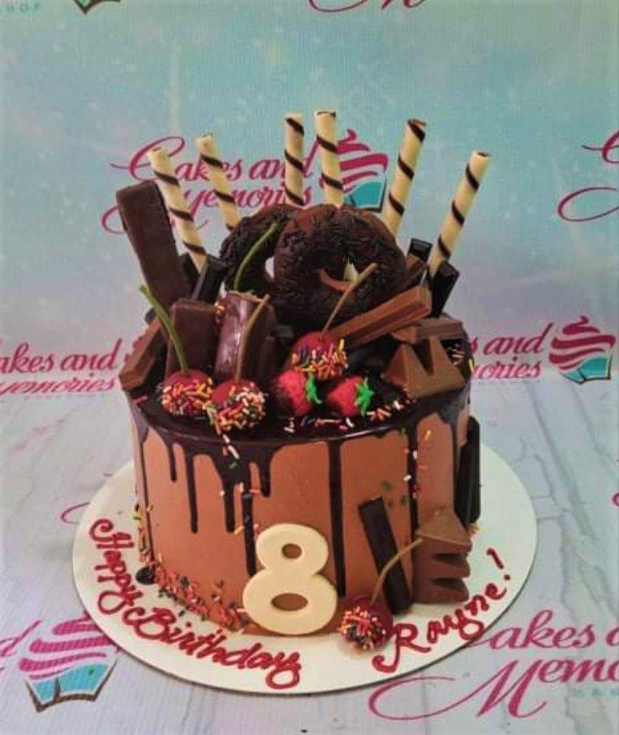 Chocolate drip cake with chocolate donuts, wafer sticks, and chocolate bars for an 8th birthday celebration.