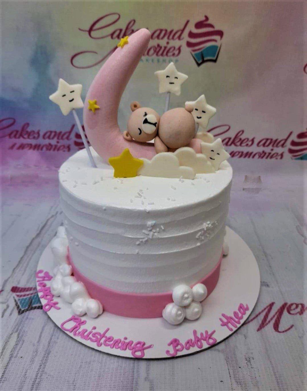 White textured 1-tier christening cake with a pink fondant moon, sleeping bear, and white stars.