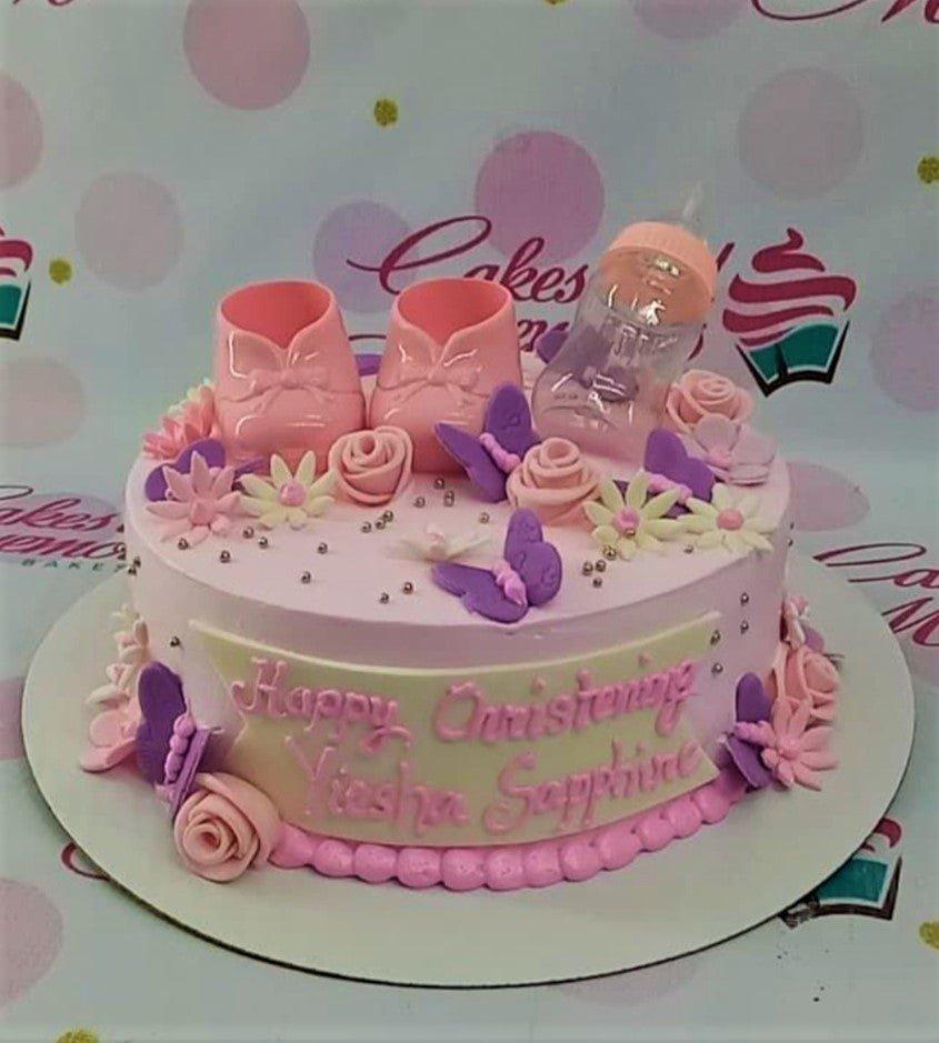 Pink christening cake for Yiesha Sapphire with baby shoes, a feeding bottle, and purple butterflies.