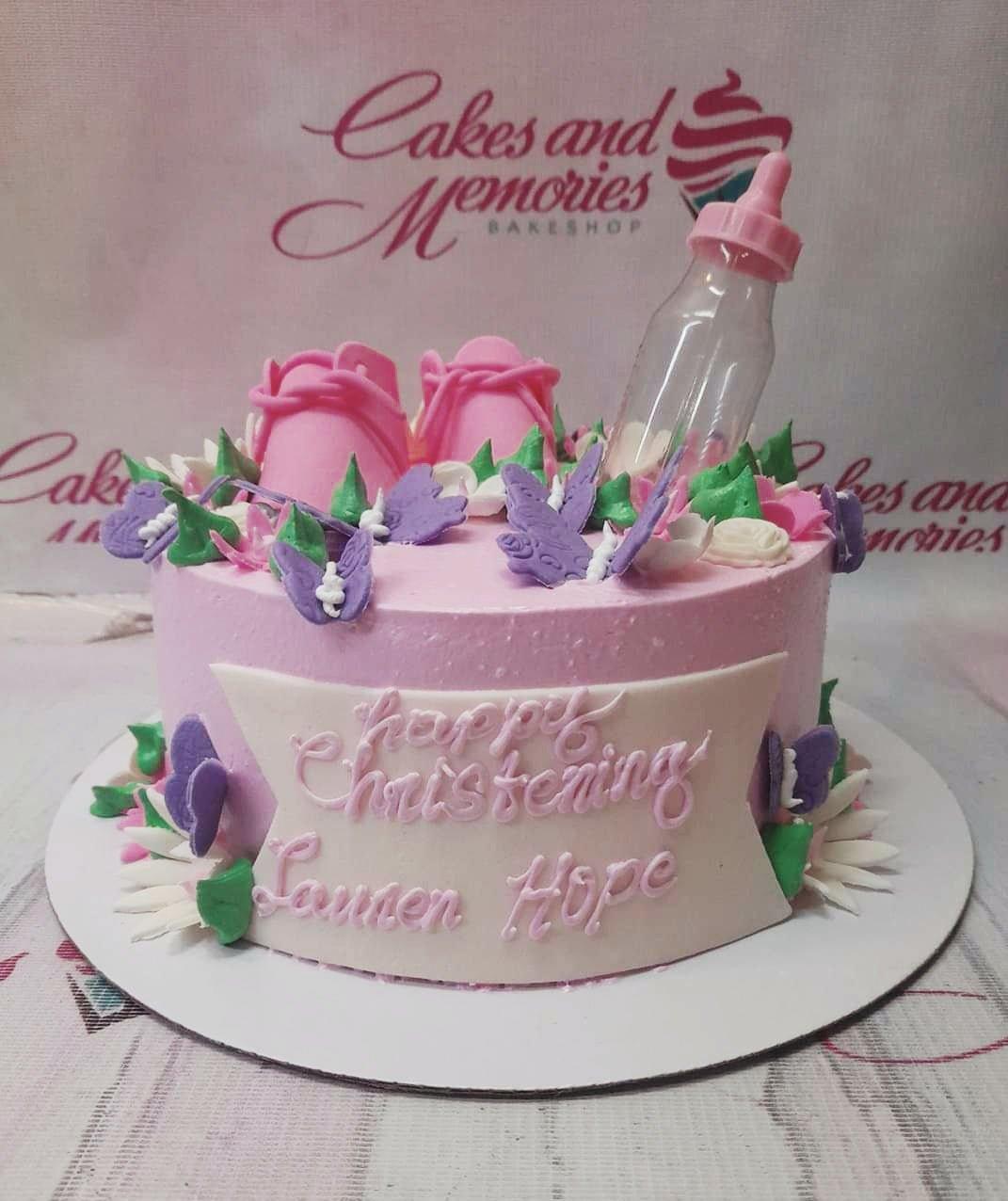 Pink christening cake for Lauren Hope with baby shoes, a bottle, and purple butterflies.
