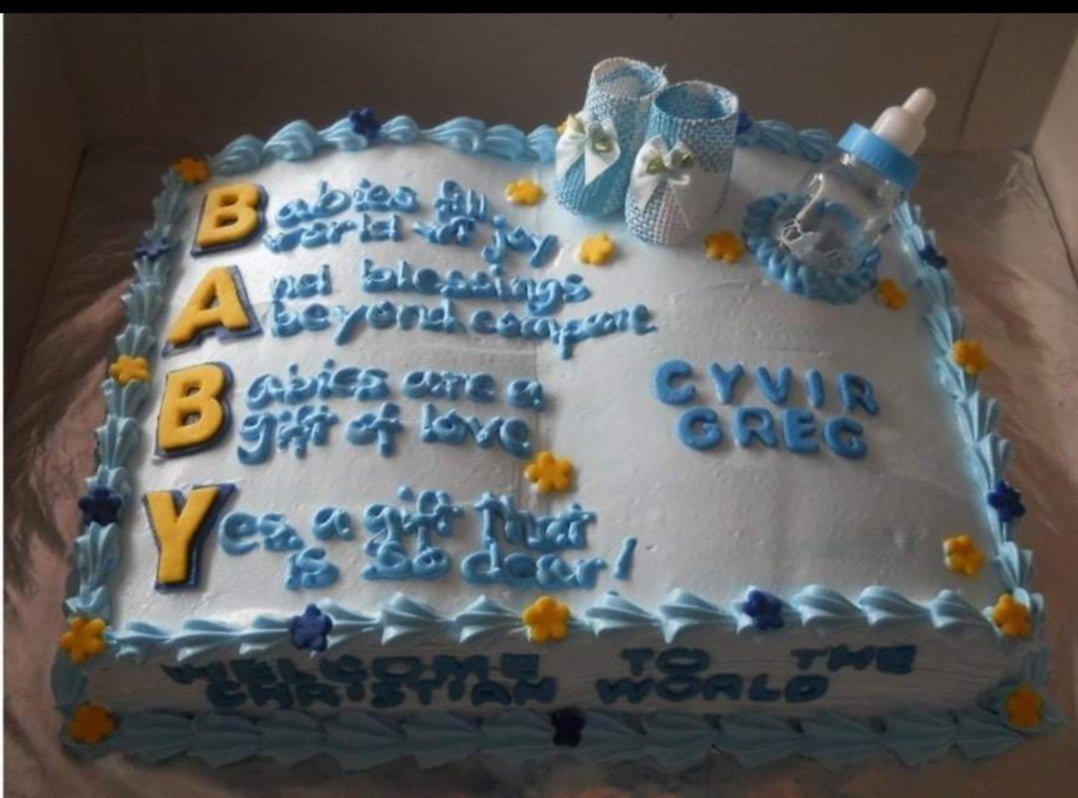 Light blue rectangular christening cake with baby booties, a bottle, and a long blue message for Cyvir Greg.