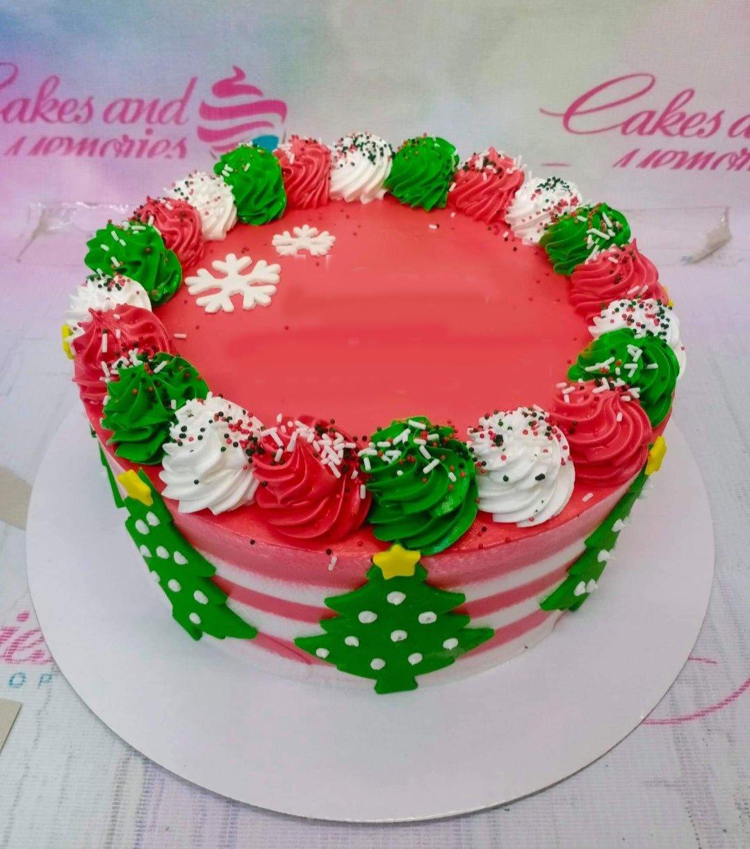 Christmas themed cake with red icing, green and white rosettes, and fondant Christmas tree and snowflake decorations.