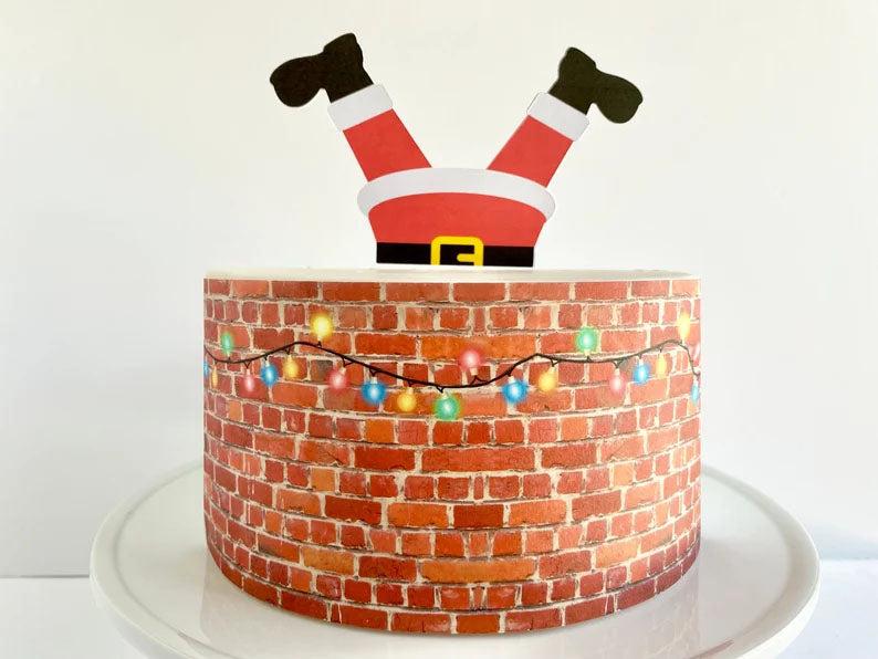 Christmas themed cake featuring a brick wall design with colorful lights and a Santa Claus topper stuck in the chimney.
