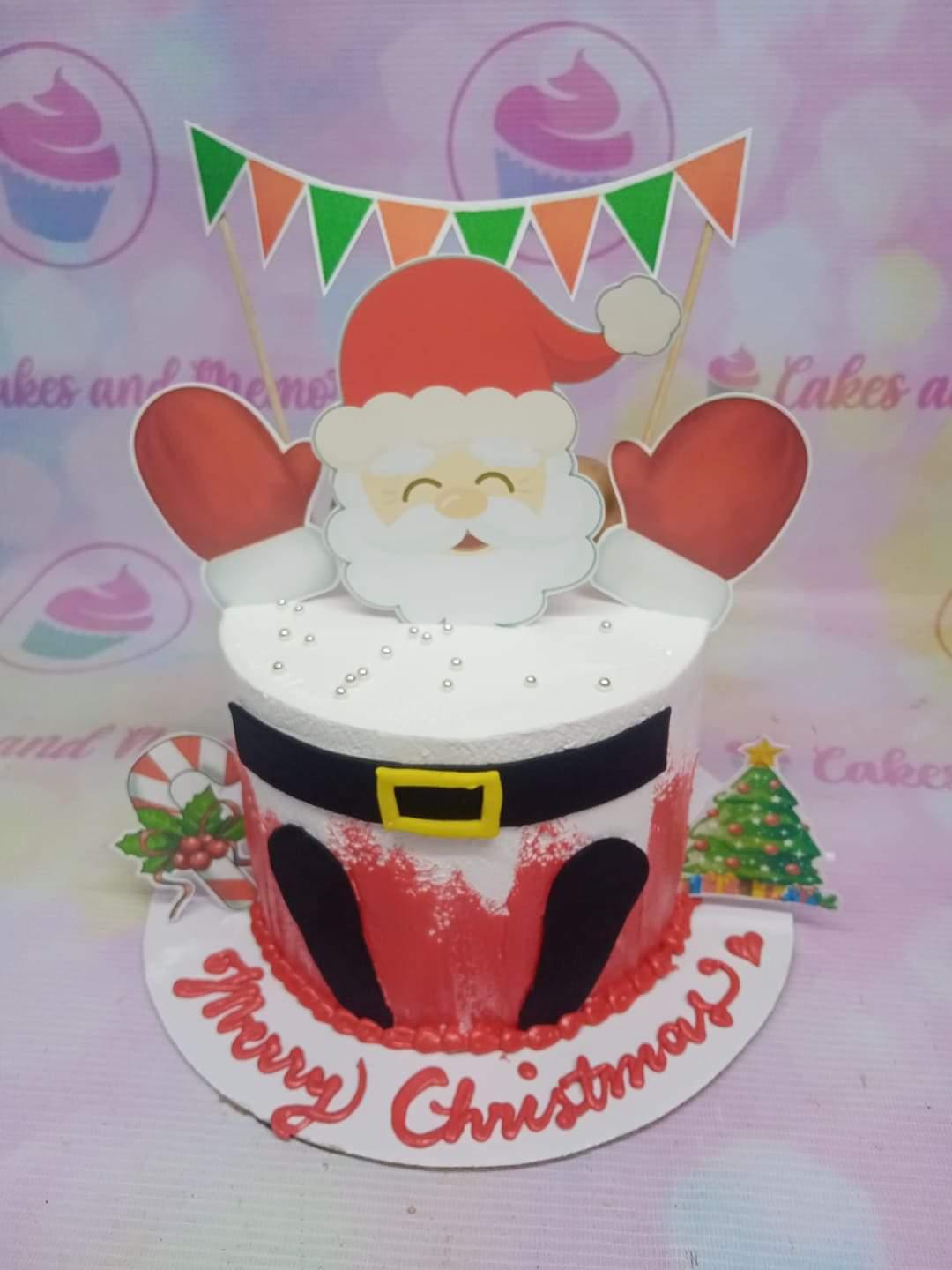 Santa Claus themed Christmas cake with red and white icing, Santa belt design, and festive printout toppers.