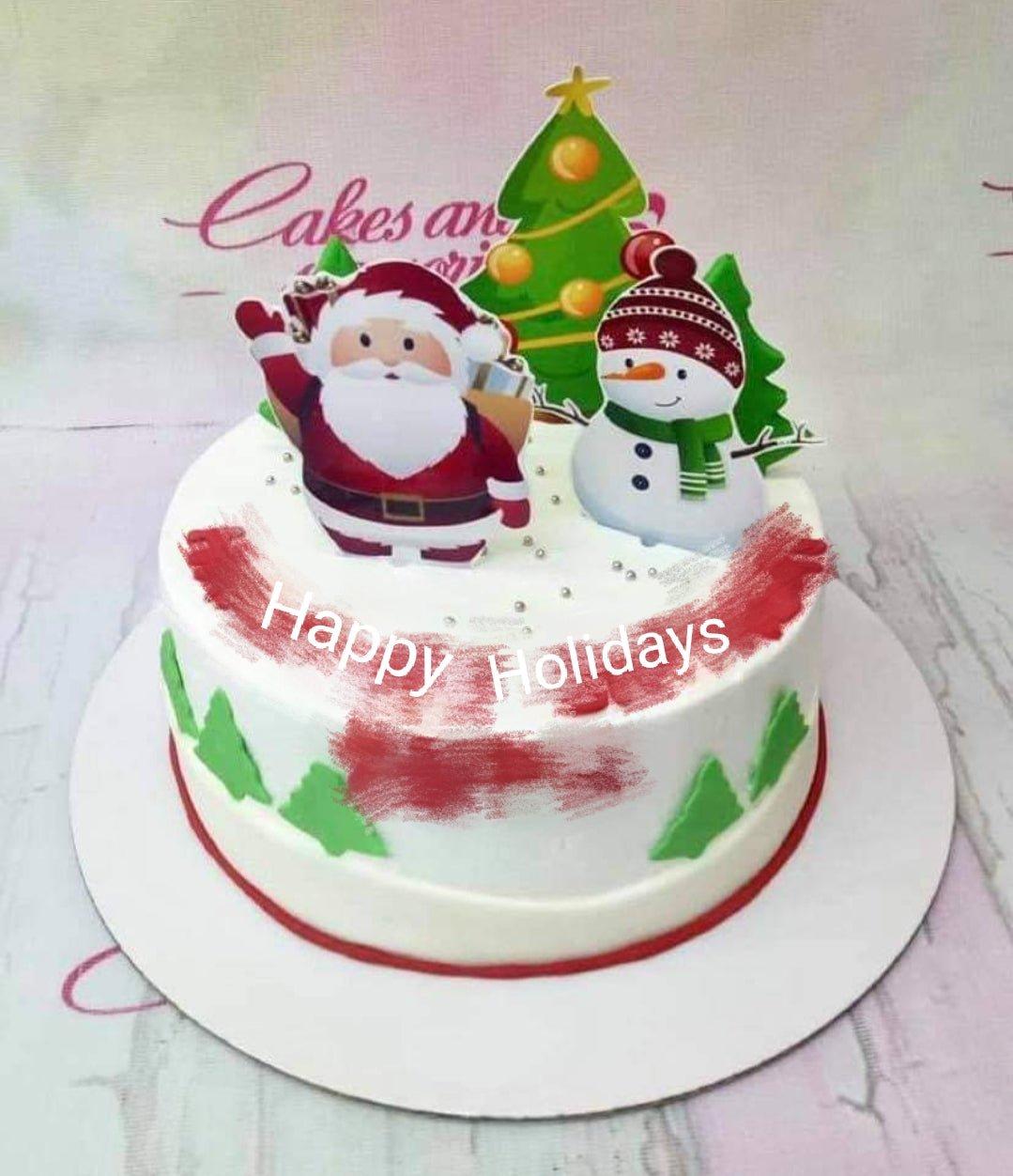 White Christmas cake with Santa Claus, snowman, and Christmas tree printout toppers and green fondant tree side decorations.