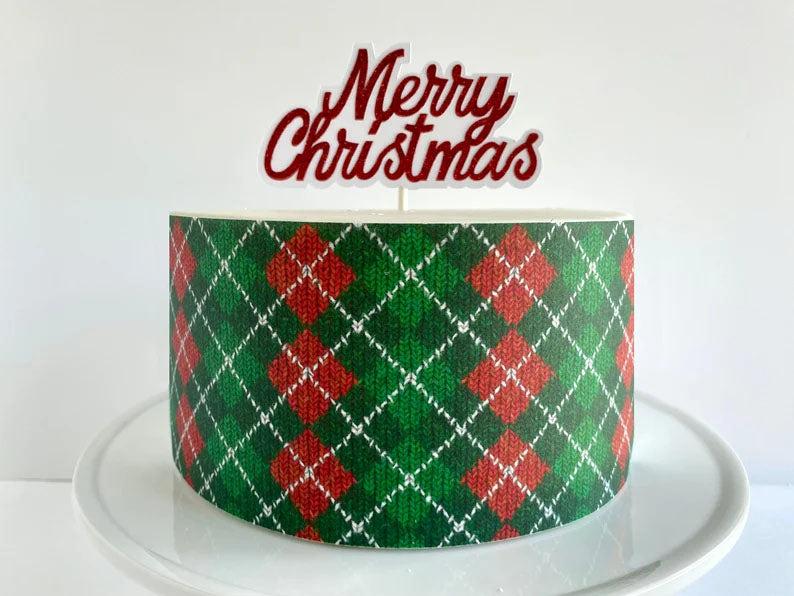 Single tier Christmas cake with a green and red argyle sweater pattern and a red glittery Merry Christmas topper.
