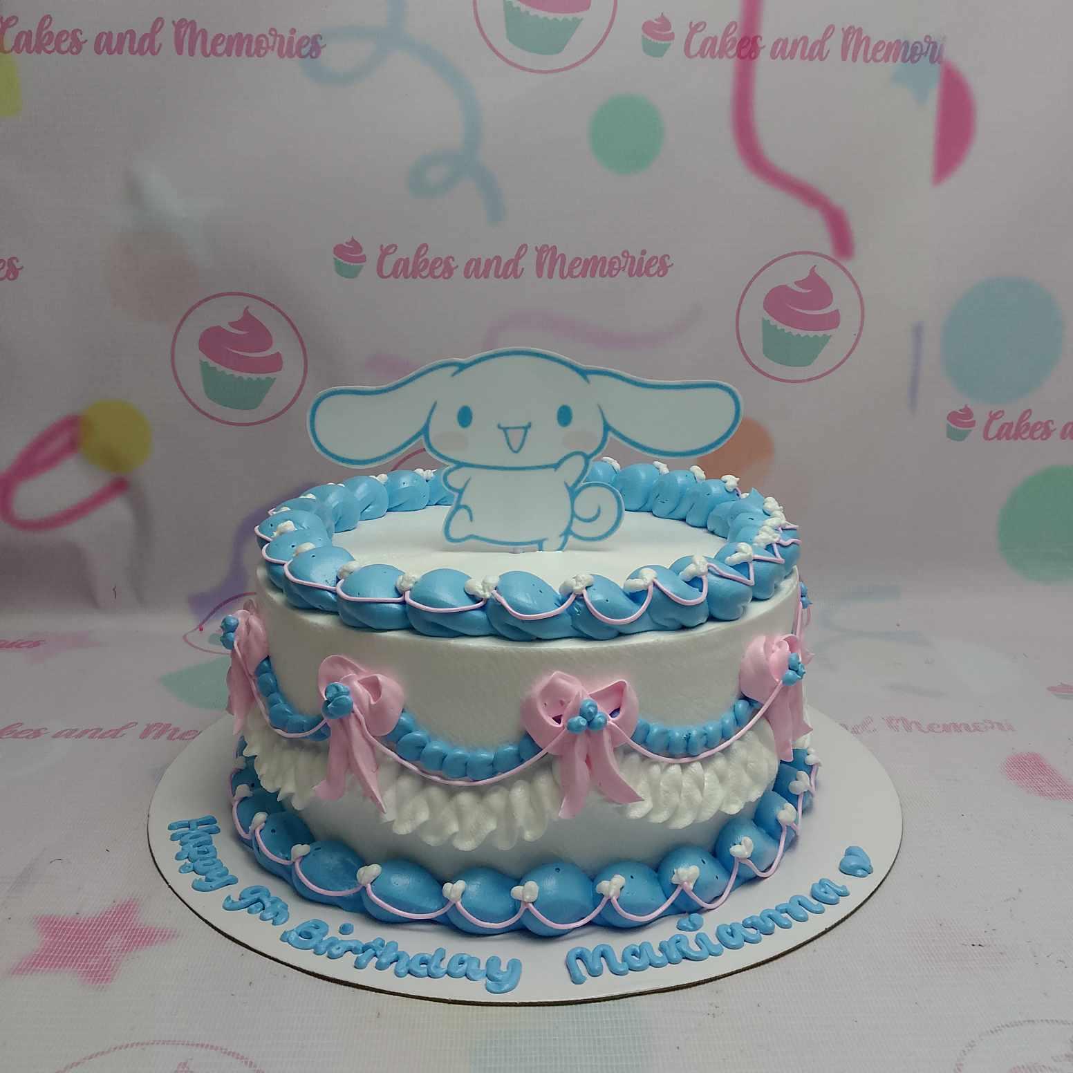 White 1-tier Cinnamoroll birthday cake with blue and pink icing ruffles, bows, and a Cinnamoroll character topper.