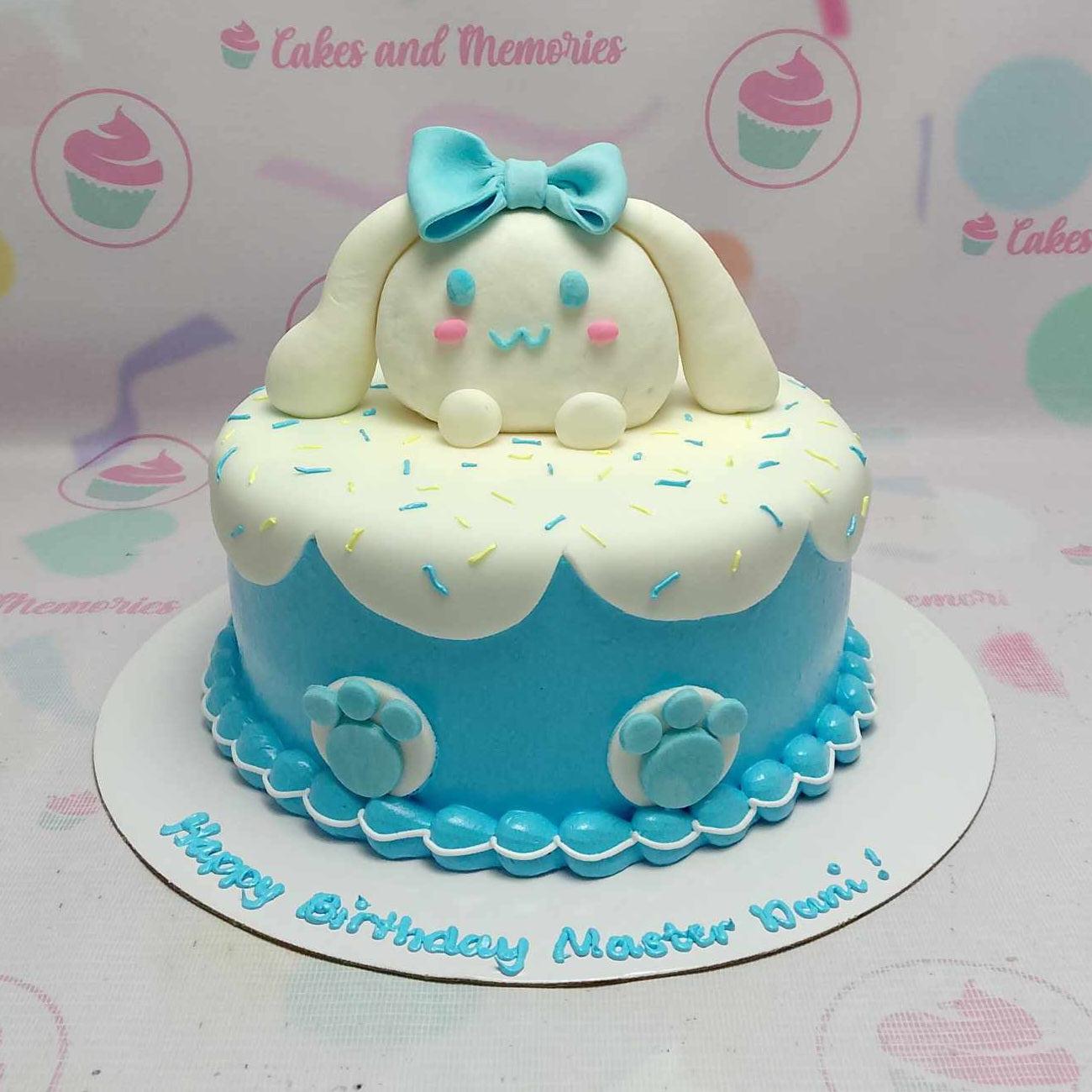 Blue and white Cinnamoroll themed birthday cake with a large fondant character topper and colorful sprinkles.