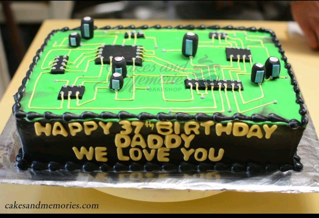 Rectangle circuit board cake with green icing, black electronic components, and a yellow birthday message for Daddy.