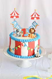 Circus themed birthday cake with red and white stripes, blue icing borders, and animal toppers including an elephant, lion, and zebra.