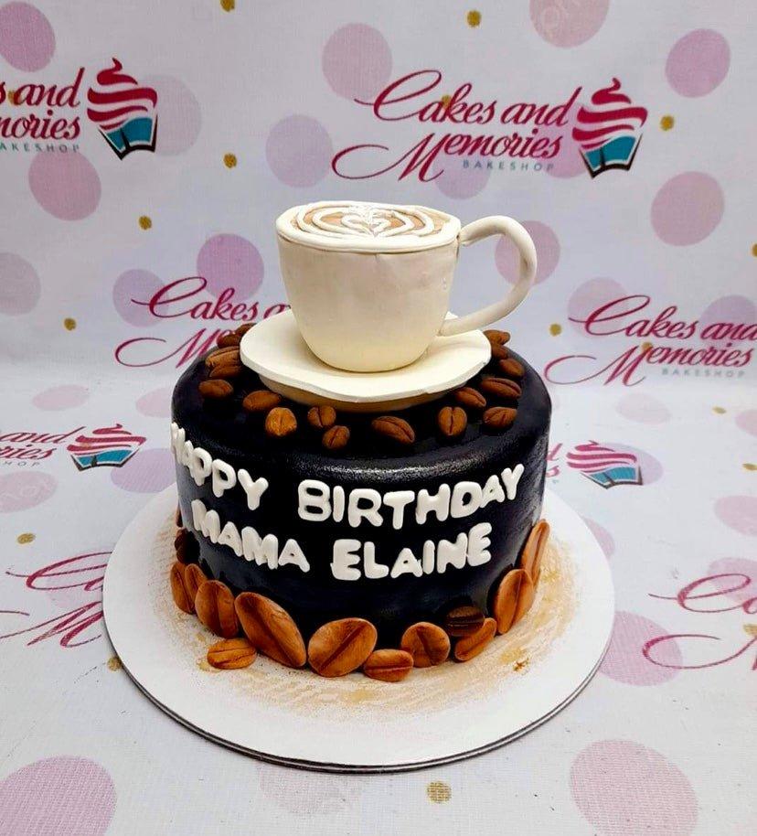 Black coffee themed birthday cake with a 3D fondant coffee cup topper and coffee bean decorations.