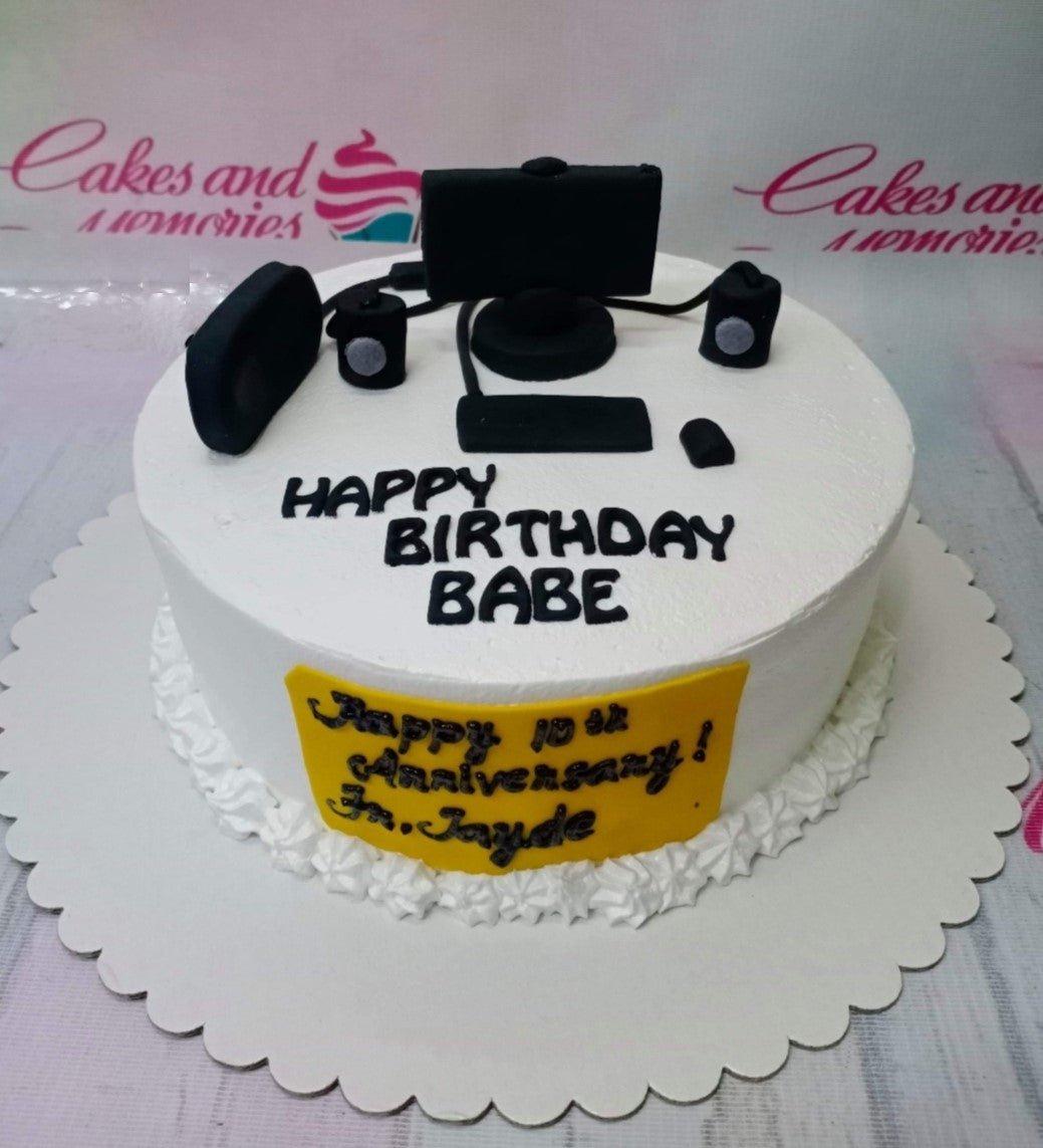 White soft-icing cake with black fondant computer setup toppers and a yellow message plaque on the side.
