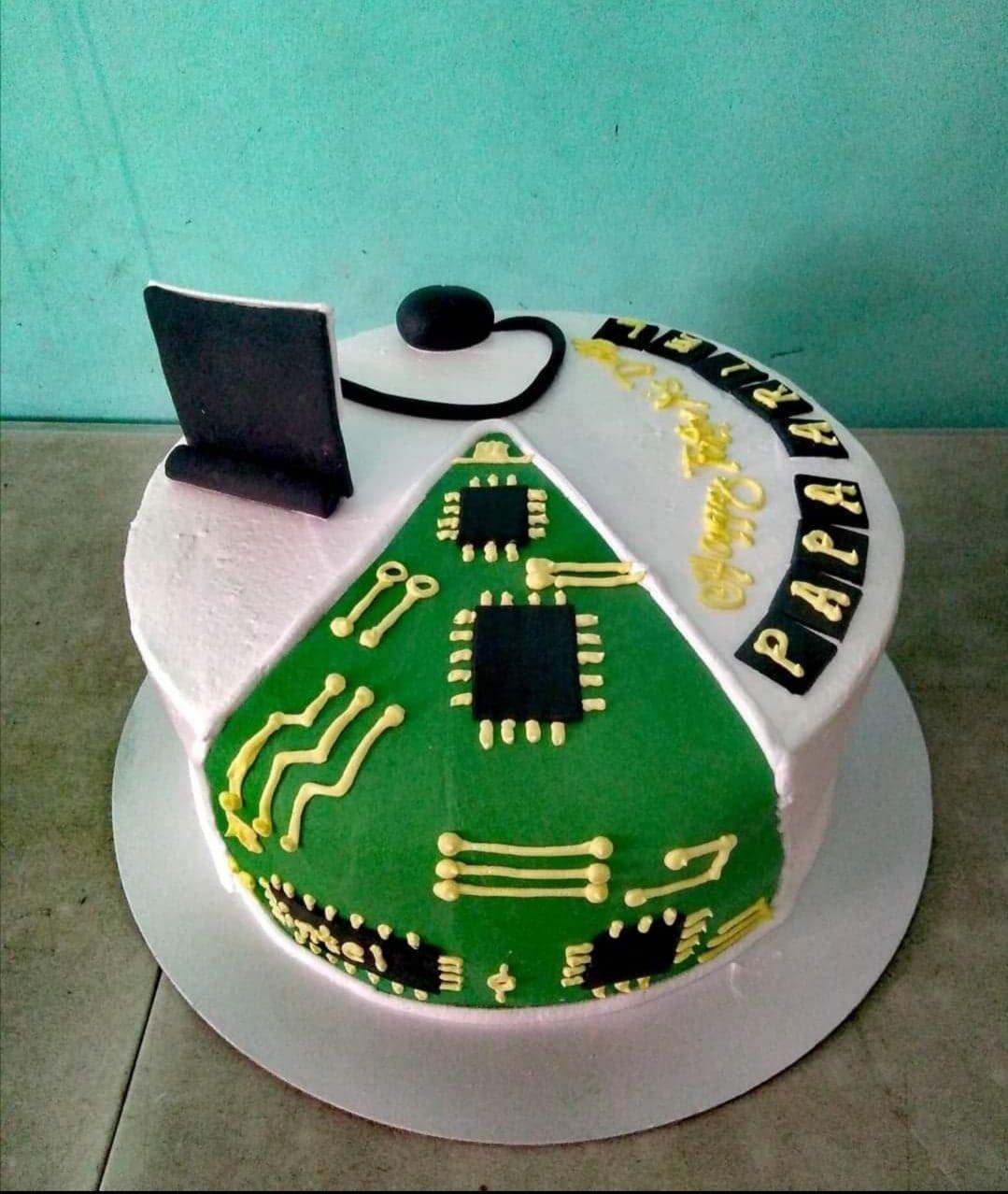 Computer motherboard themed cake with a 3D fondant laptop and mouse, featuring green circuit board icing and yellow piping.