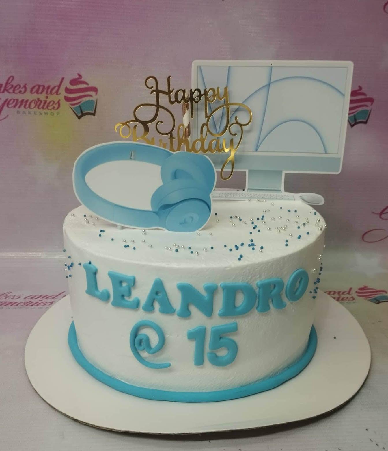 White 1-tier birthday cake for Leandro's 15th birthday featuring blue headphone and computer monitor printouts with silver and blue sprinkles.