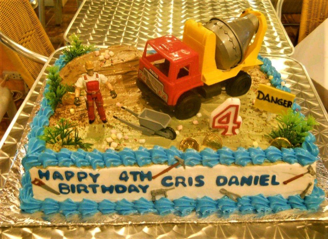 Construction themed rectangle cake with a red cement mixer toy, a construction worker figurine, and blue icing borders.