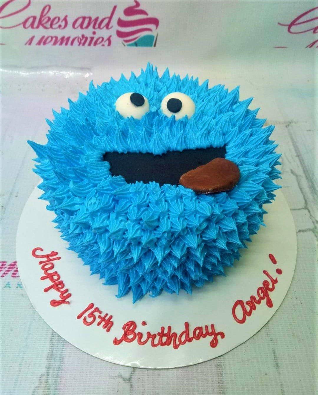 Blue Cookie Monster character cake with textured icing fur, fondant eyes, and a chocolate cookie in its mouth.