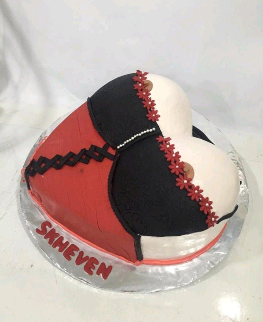 Heart-shaped corset cake in red, black, and white fondant with floral lace details and a personalized name on the base.