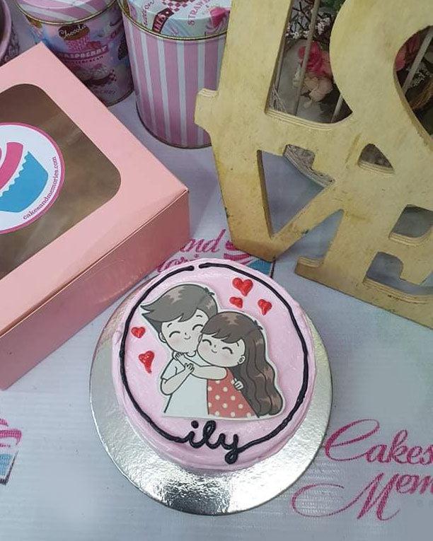 Pink bento cake with a printout of a cute hugging couple and red icing hearts.