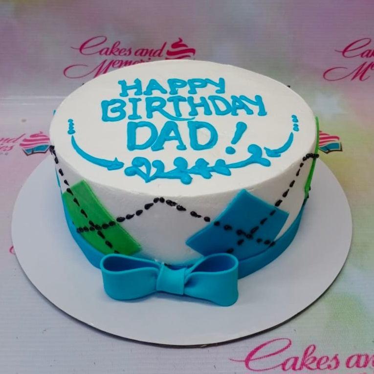 White round birthday cake for Dad with blue icing text and green and blue diamond patterns on the side.