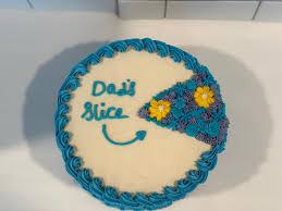 White bento cake with blue piped borders and a blue floral slice design featuring yellow flowers and 'Dad's Slice' message.
