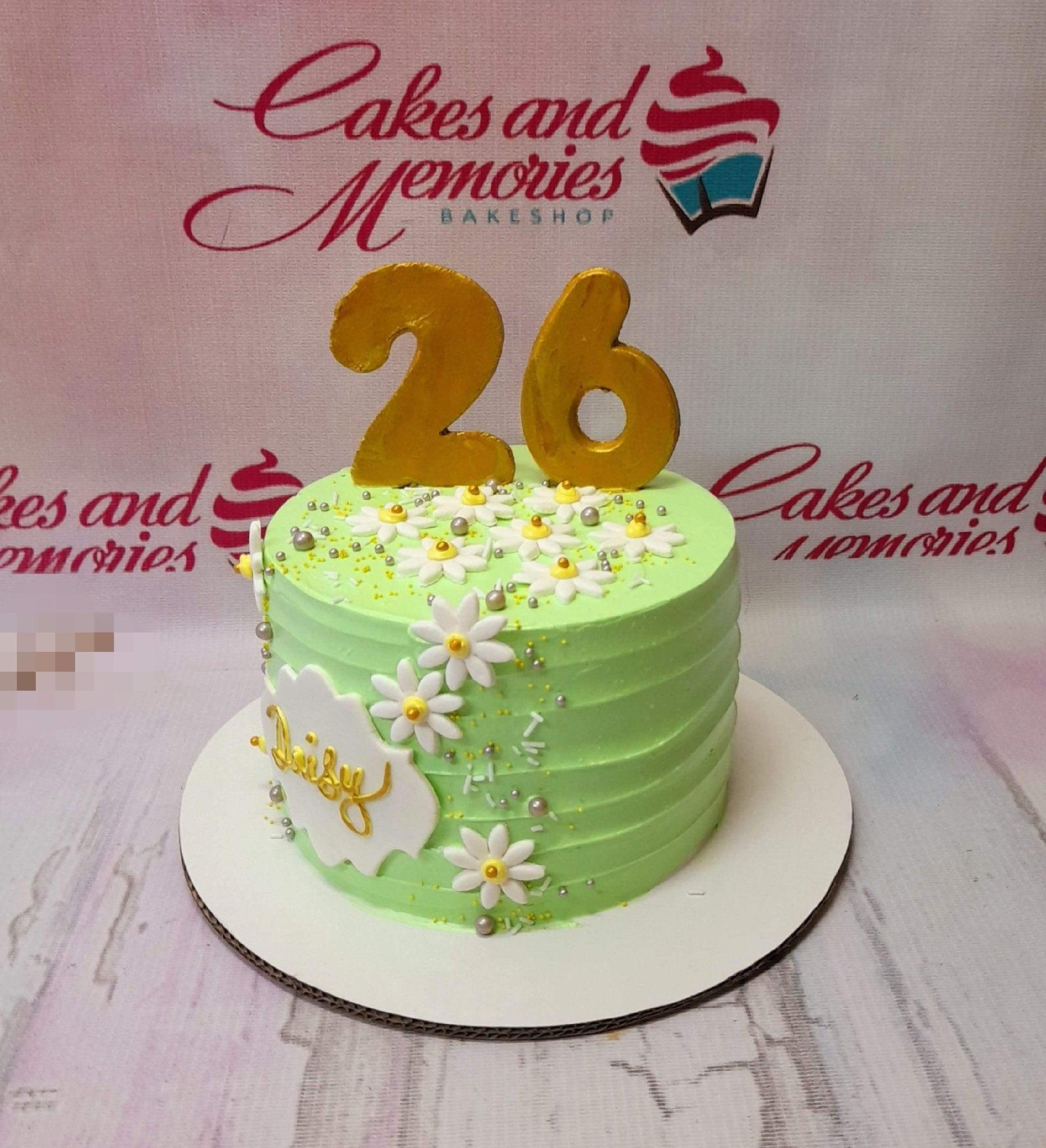 Light green 1-tier birthday cake with white fondant daisies, gold number 26 topper, and gold script name Daisy on a white plaque.