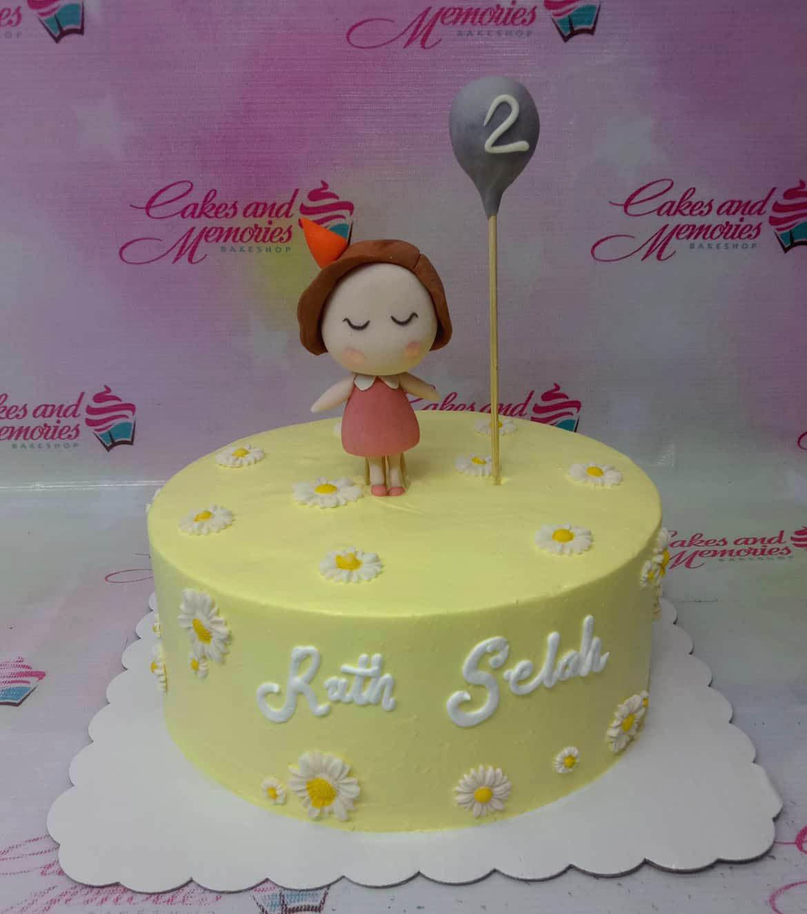 Yellow minimalist birthday cake with white daisy icing decorations and a fondant girl topper holding a grey balloon.