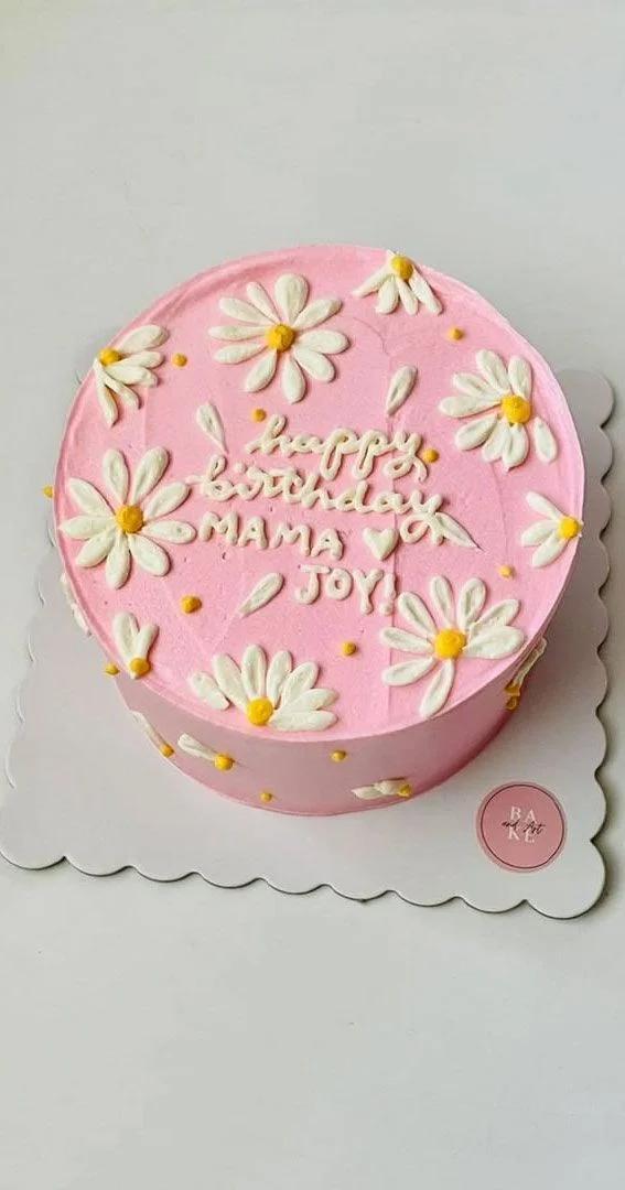 Pink bento cake with white piped icing daisies and yellow centers, featuring a Happy Birthday Mama Joy message.
