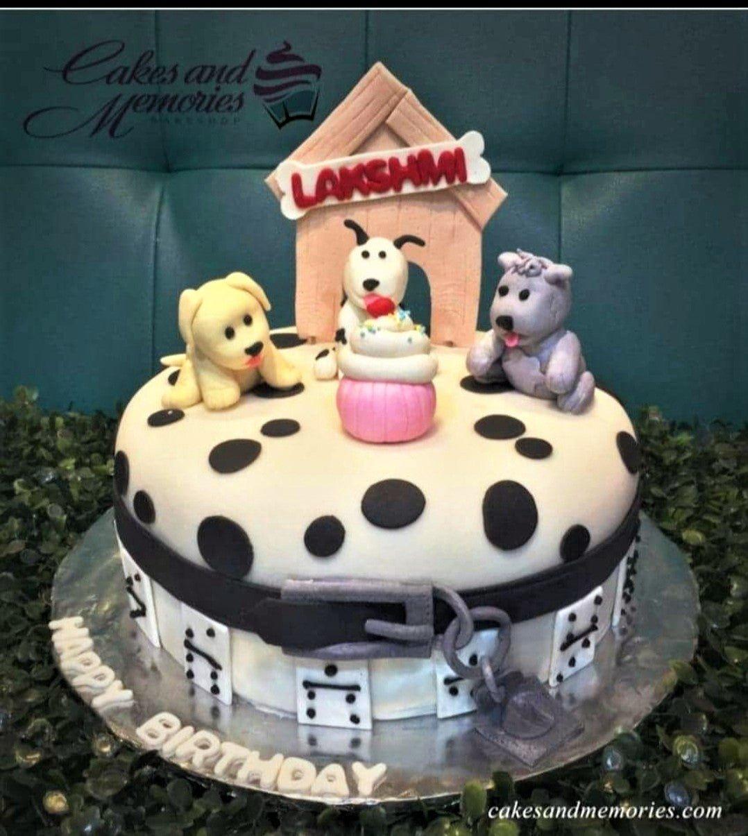 Dalmatian themed birthday cake with three fondant dogs, a dog house, and a pink cupcake topper on a white cake with black spots.