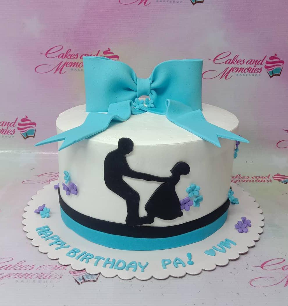 White minimalist cake with a large blue fondant bow and a black silhouette of a dancing couple, accented with purple and teal flowers.