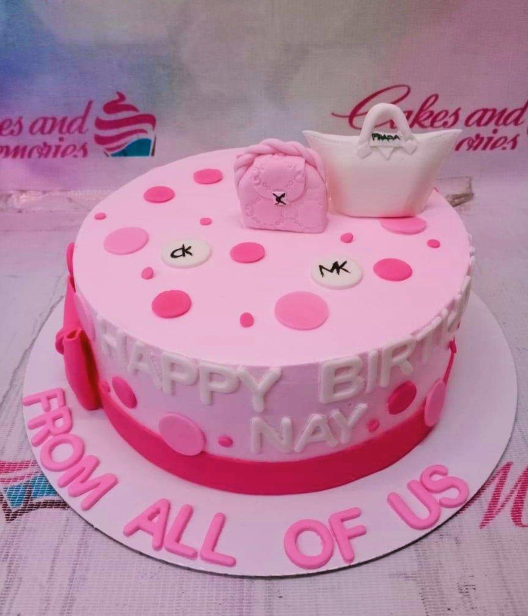 Pink fondant birthday cake with pink and white designer bag toppers and polka dot patterns.