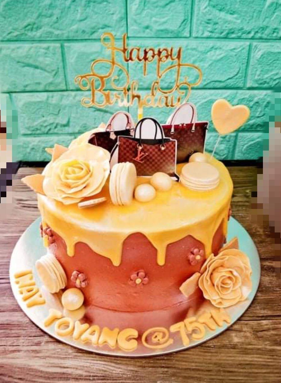 Brown and gold luxury designer bag themed cake with yellow drip and edible roses for a 75th birthday celebration.