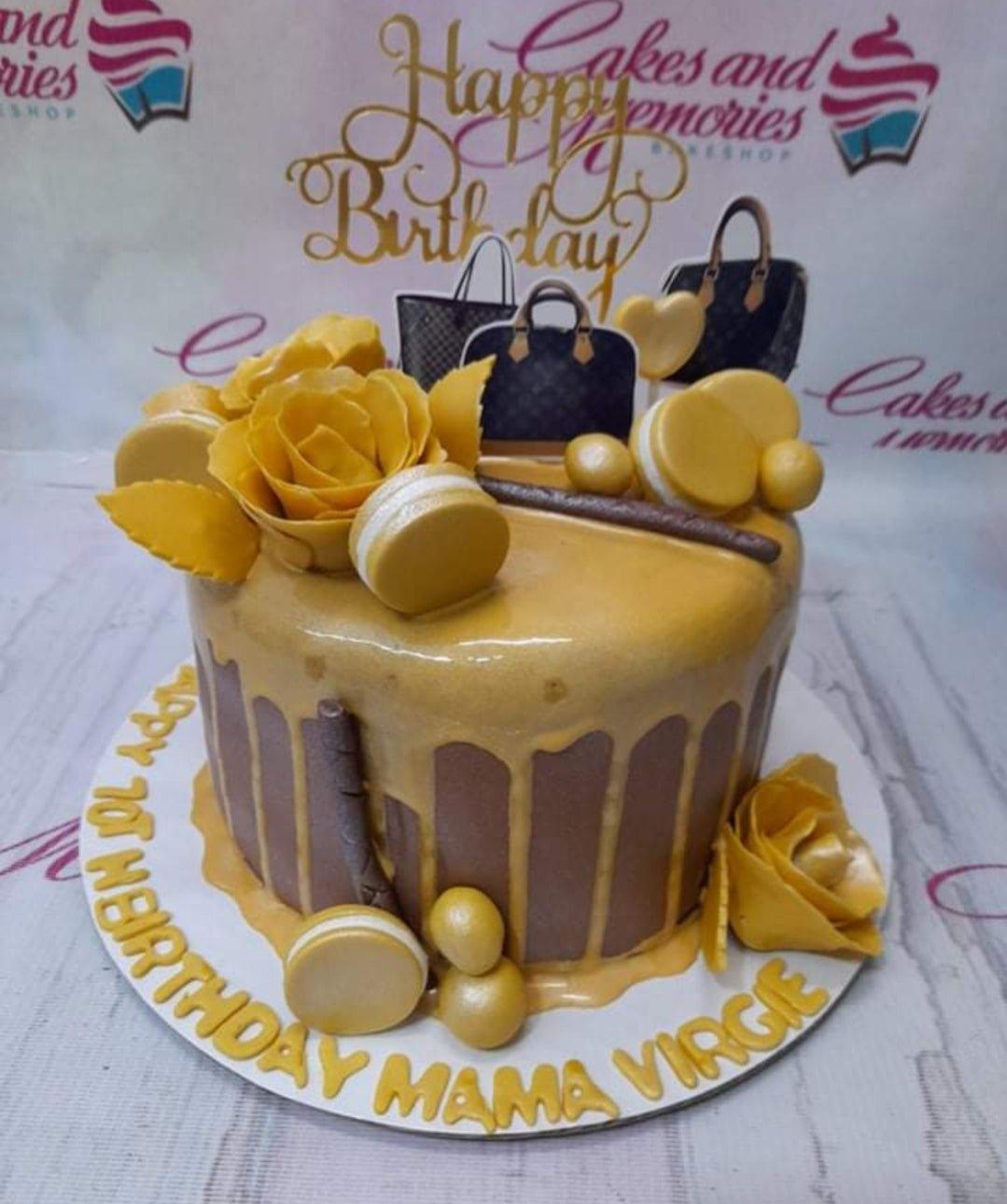 Brown and gold drip cake with designer bag printouts, yellow roses, and macarons for a 70th birthday celebration.